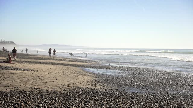 The beach, the surf and the ocean at Leucadia, with people walking.