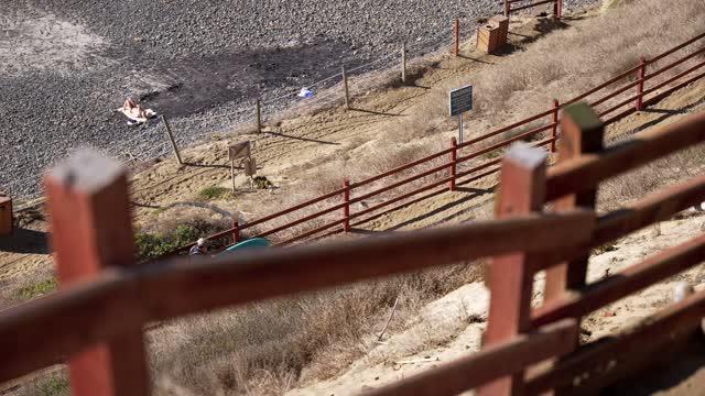 Elevated view of the cliffs, the beach and open country at Leucadia, with people walking.