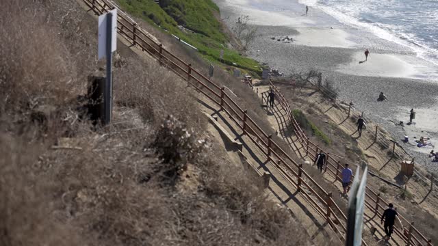 Elevated view of the cliffs, the ocean and the beach at Leucadia, with people walking.