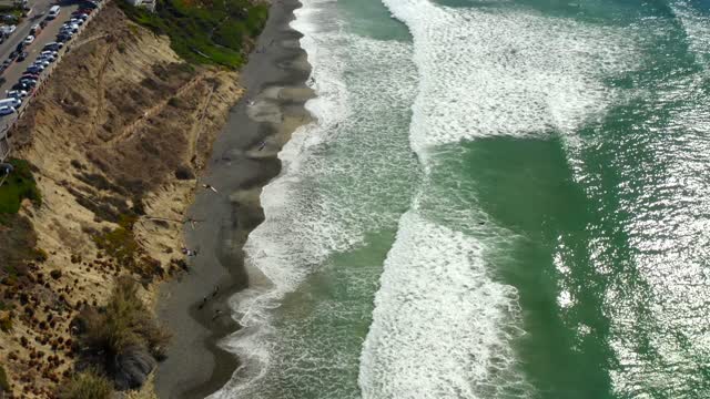 Aerial view of the beach, the surf and the ocean at Leucadia, with people walking.