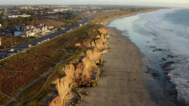 Aerial view of the cliffs, the ocean and homes in Carlsbad, with people walking.