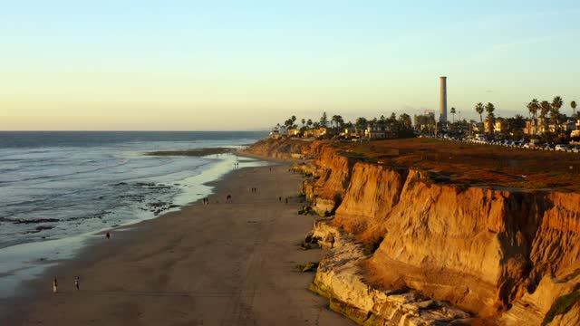 Aerial view of the cliffs, palm trees and the ocean in Carlsbad, with people walking.