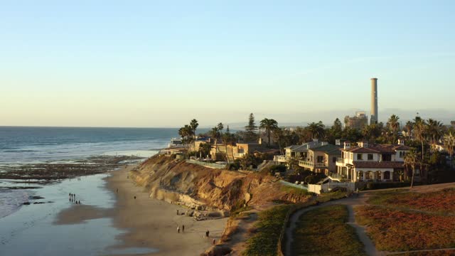 Aerial view of the cliffs, palm trees and the ocean in Carlsbad, with people walking.