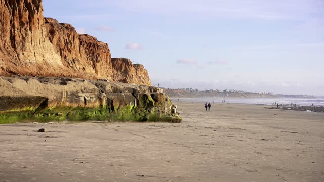 The beach, the ocean and the cliffs in Carlsbad, with people walking.