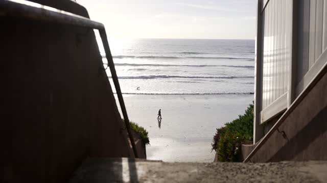 Elevated view of the beach, the surf and the ocean in Carlsbad, with people walking.