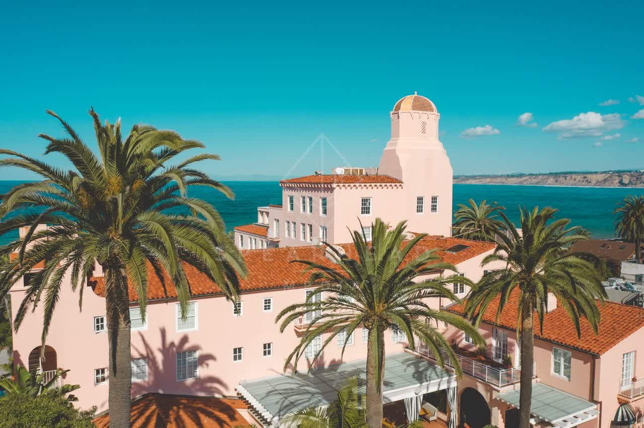 Low aerial view of the beach, palm trees and the ocean at La Jolla Cove.