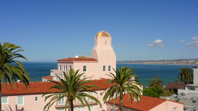 Low aerial view of the downtown streets, palm trees and the ocean at La Jolla Cove.
