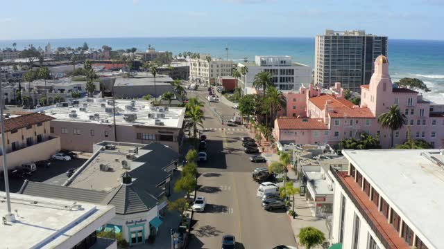 Low aerial view of the downtown streets, palm trees and the ocean at La Jolla Cove.