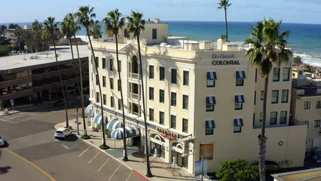 Low aerial view of the downtown streets, palm trees and the ocean at La Jolla Cove.