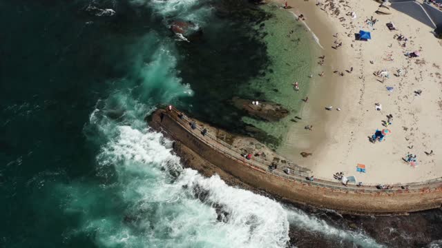 Aerial view of the beach, the surf and the ocean at La Jolla Cove, with a crowd gathered.