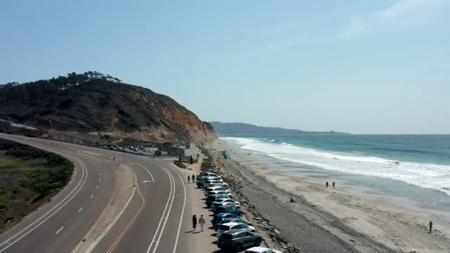Low aerial view of the beach, the surf and the ocean at Torrey Pines, with people walking.