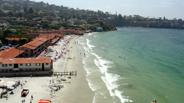 Low aerial view of the beach, the surf and the ocean at La Jolla Shores, with swimmers in the water.