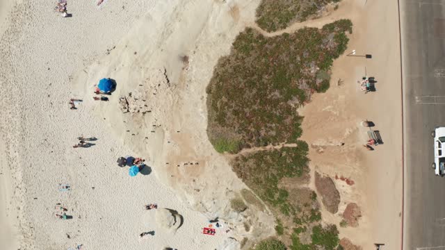 Aerial view of the beach, traffic and open country at Windansea, with a crowd gathered.