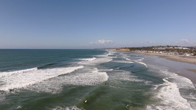 Aerial view of the beach, the surf and the ocean at Powerhouse Park, with surfers out.