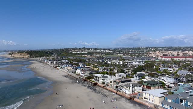 Aerial view of the beach, palm trees and the ocean at Powerhouse Park, with people walking.