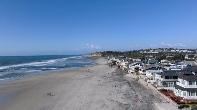Low aerial view of the beach, the surf and the ocean at Powerhouse Park, with people walking.