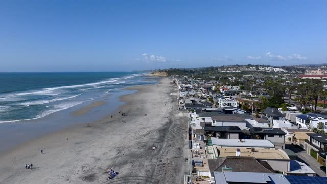 Aerial view of the beach, the surf and palm trees at Powerhouse Park, with people walking.