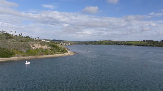 Low aerial view of the country inland, boats and the bay in Carlsbad, with boats out.