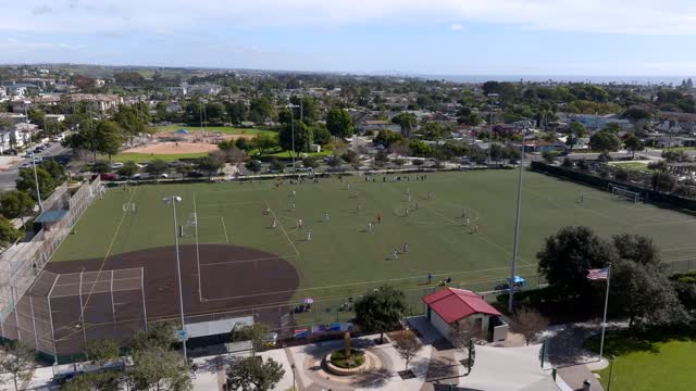 Aerial view of a park, homes and traffic in Carlsbad, with swimmers in the water.