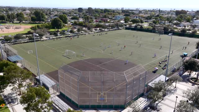 Low aerial view of a park, homes and traffic in Carlsbad, with swimmers in the water.