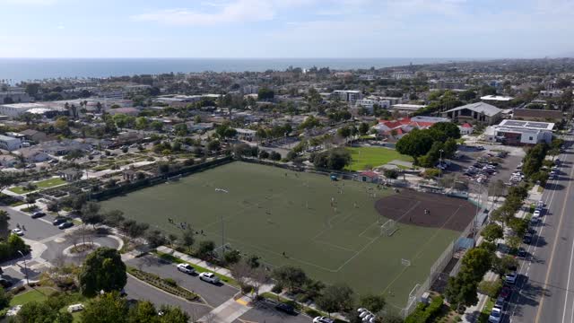 Aerial view of a residential street, the ocean and homes in Carlsbad, with a crowd gathered.