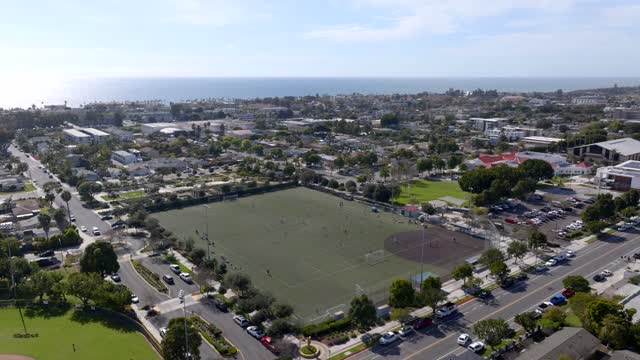 Aerial view of a residential street, the ocean and homes in Carlsbad, with swimmers in the water.