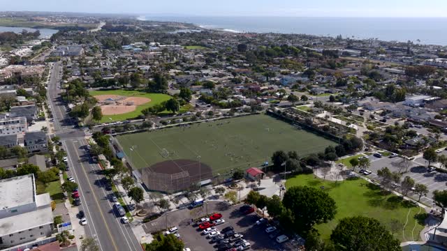 Aerial view of a residential street, the ocean and homes in Carlsbad, with a crowd gathered.