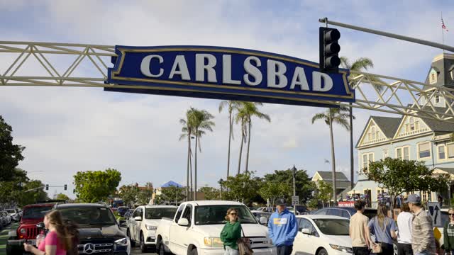 The downtown streets, palm trees and homes in Carlsbad, with people walking.