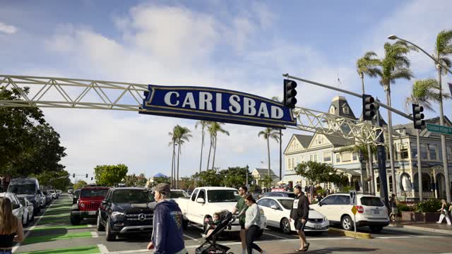 The downtown streets, palm trees and the buildings in Carlsbad, with people walking.