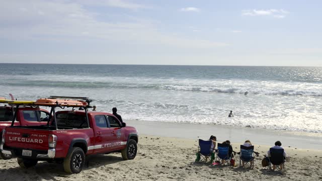 The beach, the surf and the ocean in Carlsbad, with a crowd gathered.