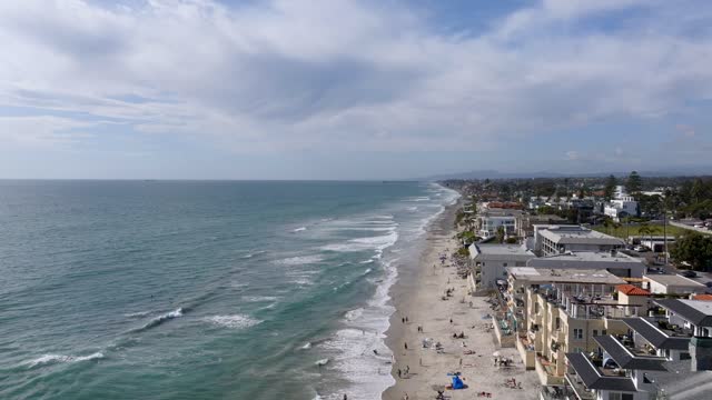 Aerial view of the beach, the surf and the ocean in Carlsbad, with people walking.