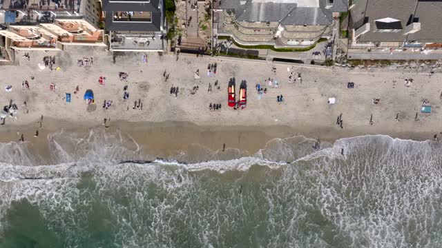 Aerial view of the beach, the surf and the ocean in Carlsbad, with people walking.