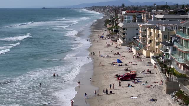 Aerial view of the beach, the surf and the ocean in Carlsbad, with people walking.