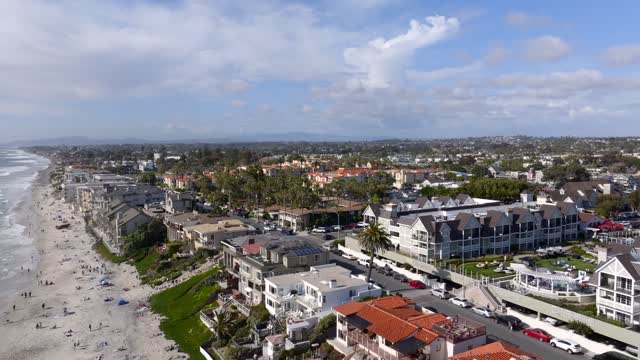 Aerial view of the beach, palm trees and the ocean in Carlsbad, with people walking.