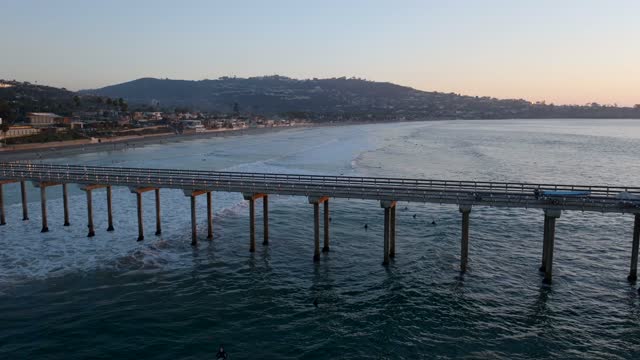 Low aerial view of the beach, the surf and the pier at La Jolla Shores.