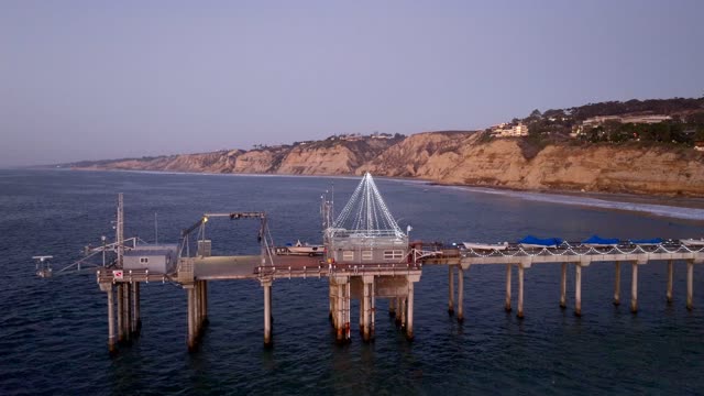 Low aerial view of the harbor, the pier and boats at La Jolla Shores.