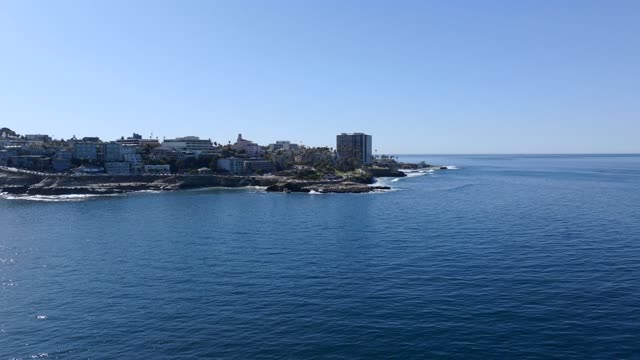 Low aerial view of the cliffs, the ocean and homes at La Jolla Cove.