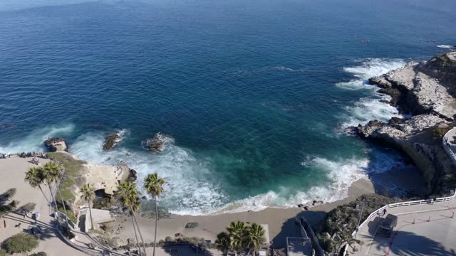 Aerial view of the cliffs, the surf and palm trees at La Jolla Cove.