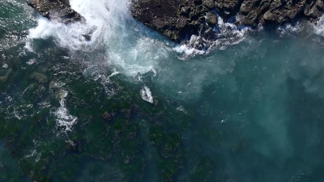Aerial view of the cliffs, the surf and the ocean at La Jolla Cove.