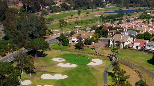 Aerial view of a residential street, palm trees and homes in Rancho Santa Fe, with people walking.
