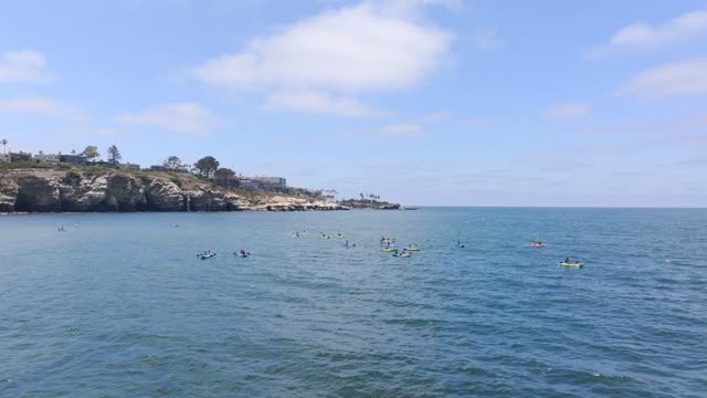 Aerial footage of People in colorful Kayaks exploring the beautiful coastline of La Jolla and La Jolla Cove on a sunny day | Drone Video