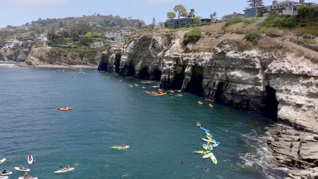 Aerial footage of People in colorful Kayaks exploring the beautiful coastline of La Jolla and La Jolla Cove on a sunny day | Drone Video – 1