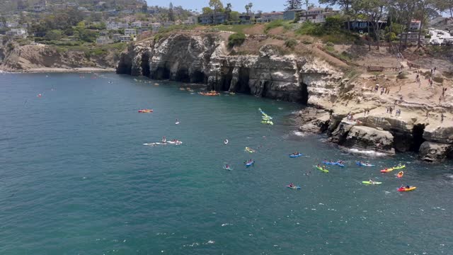 Aerial footage of People in colorful Kayaks exploring the beautiful coastline of La Jolla and La Jolla Cove on a sunny day | Drone Video – 2