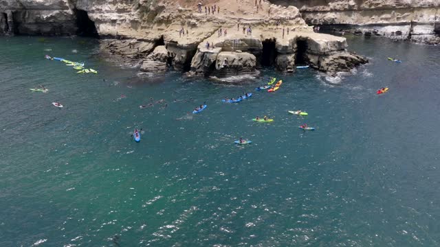 Aerial footage of People in colorful Kayaks exploring the beautiful coastline of La Jolla and La Jolla Cove on a sunny day | Drone Video – 3
