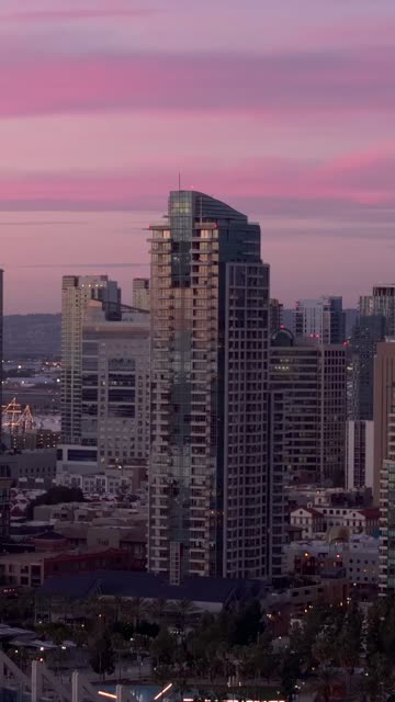 Aerial view of the Pinnacle Marina Tower in the Marina District downtown San Diego during sunset | Vertical Drone Video