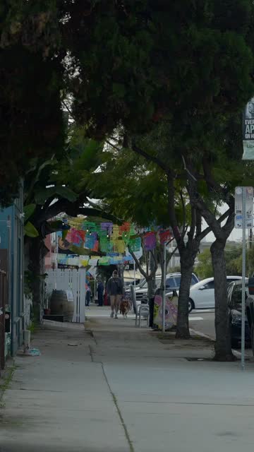 A residential street, homes and traffic in Barrio Logan, with people walking.