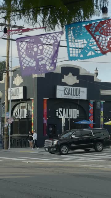 The downtown streets, the buildings and traffic in Barrio Logan, with people walking.
