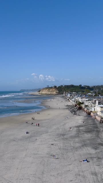 Aerial view of the beach, the surf and the ocean at Powerhouse Park, with people walking.