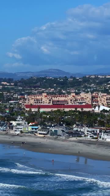 Aerial view of the beach, the surf and palm trees in Del Mar, with people walking.
