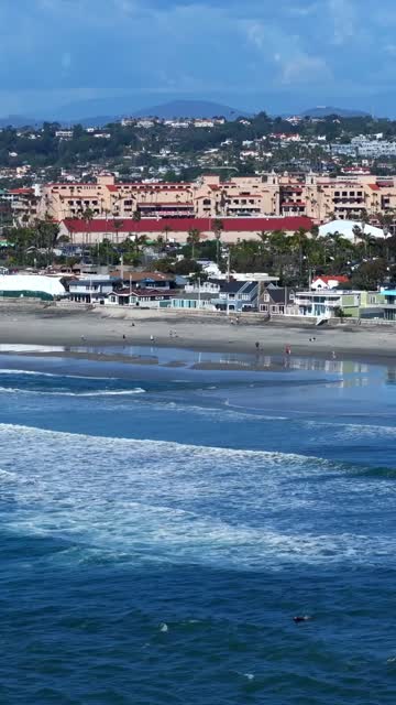 Aerial view of the beach, the surf and the ocean in Del Mar, with people walking.